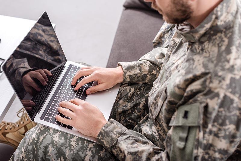 a man in camouflage using a laptop computer